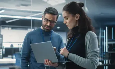 Team of cybersecurity professionals reviewing security implementation on laptop