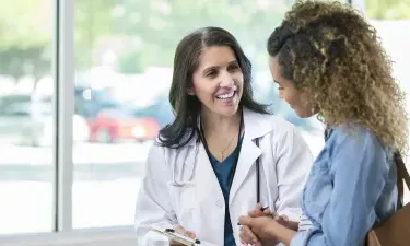 Women's health nurse practitioner smiling with patient during appointment